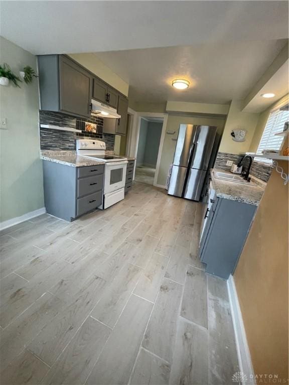 50 Woodcrest Ave, Dayton, OH 45405 - kitchen with decorative backsplash, under cabinet range hood, a sink, white range with electric cooktop, and freestanding refrigerator
