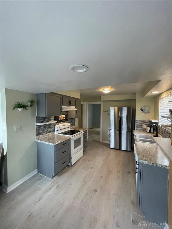 50 Woodcrest Ave, Dayton, OH 45405 - kitchen with backsplash, a sink, freestanding refrigerator, gray cabinetry, and white electric range