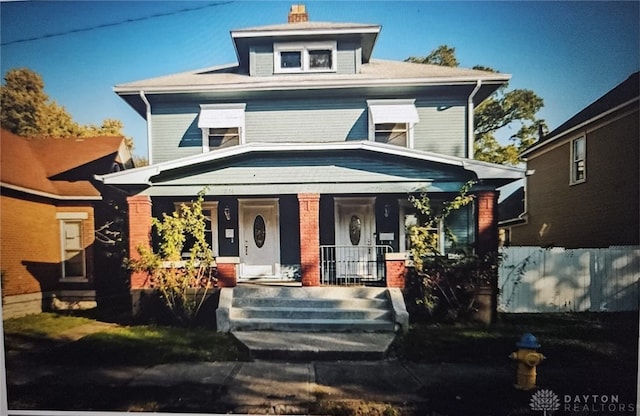 traditional style home featuring covered porch and a chimney