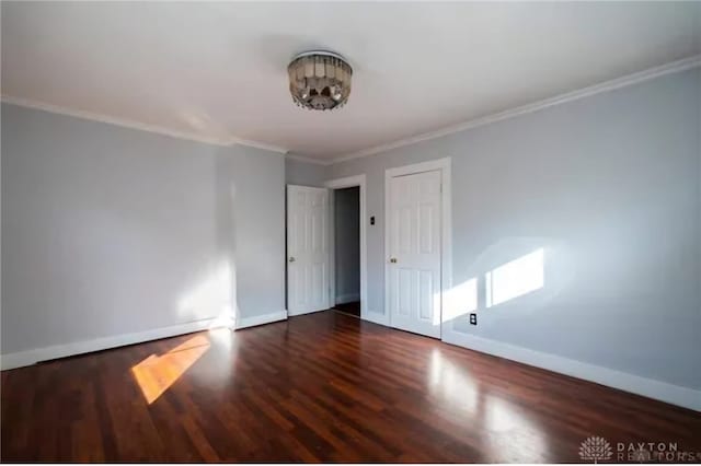 unfurnished room featuring crown molding, baseboards, and wood finished floors