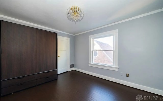 unfurnished bedroom featuring visible vents, baseboards, dark wood-type flooring, crown molding, and a closet