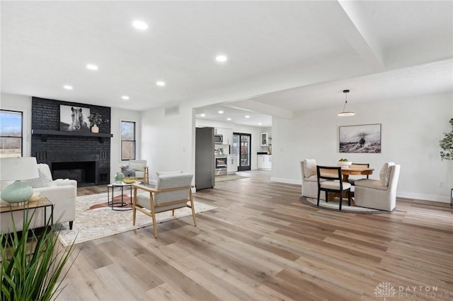 living area with light wood-type flooring, visible vents, a fireplace, and recessed lighting