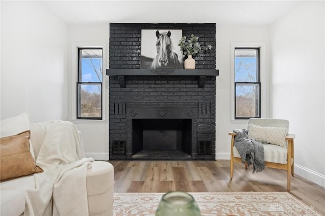 living area with a fireplace, baseboards, and wood finished floors