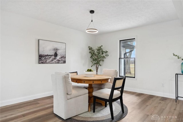 dining space featuring a textured ceiling, baseboards, and wood finished floors