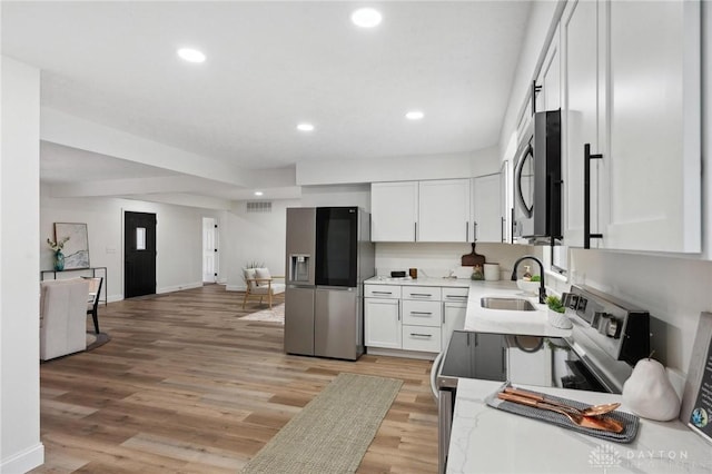 kitchen featuring recessed lighting, a sink, white cabinetry, appliances with stainless steel finishes, and light wood finished floors