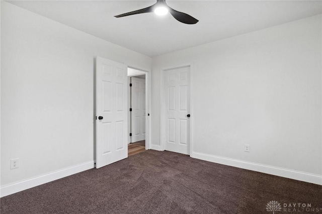 unfurnished bedroom featuring baseboards, dark carpet, and a ceiling fan