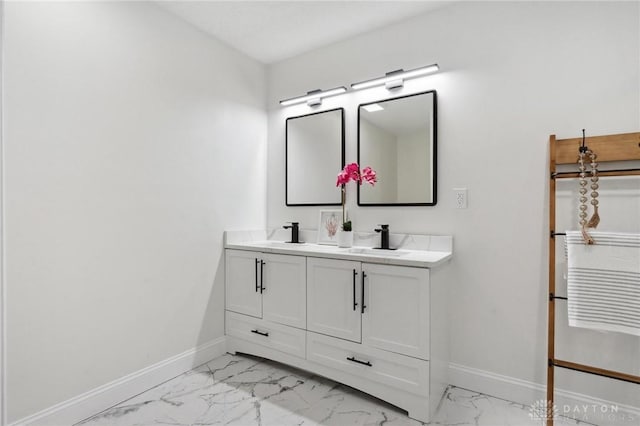 bathroom featuring marble finish floor, a sink, baseboards, and double vanity