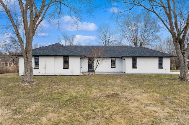 rear view of property with roof with shingles and a yard