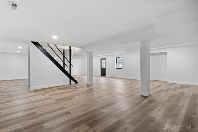 below grade area featuring light wood finished floors, visible vents, stairway, and baseboards