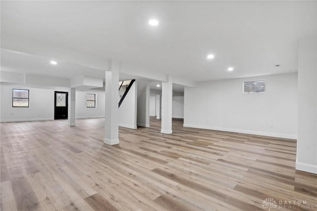 basement featuring baseboards, light wood-style flooring, and recessed lighting