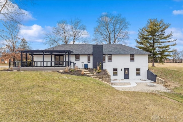 back of property with stucco siding, central AC, a pergola, and a yard