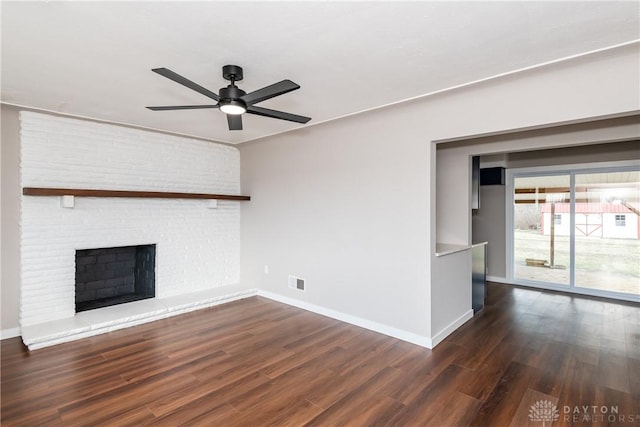 unfurnished living room with a fireplace, dark wood finished floors, visible vents, and baseboards