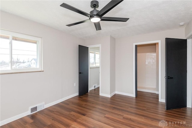 unfurnished bedroom with visible vents, a textured ceiling, baseboards, and wood finished floors