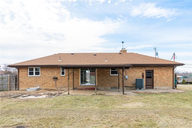 back of house with brick siding, a patio, central air condition unit, a lawn, and fence