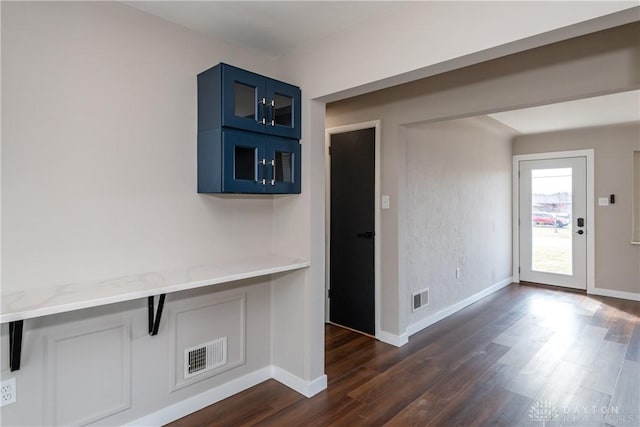 interior space with dark wood-style floors, visible vents, and baseboards