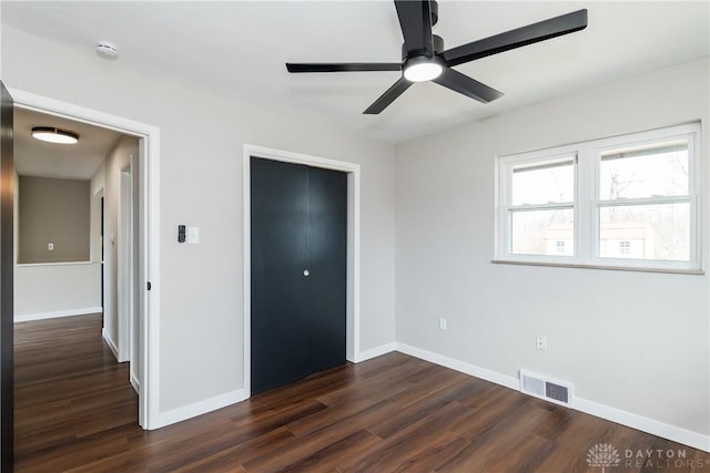 unfurnished bedroom featuring dark wood-type flooring, a closet, visible vents, and baseboards