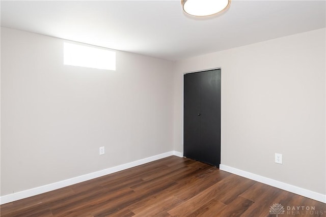 empty room with dark wood-type flooring and baseboards