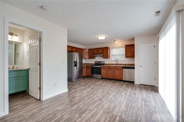 kitchen with under cabinet range hood, visible vents, appliances with stainless steel finishes, and wood finished floors