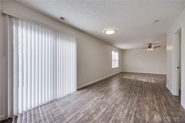 spare room with a textured ceiling, wood finished floors, visible vents, and baseboards