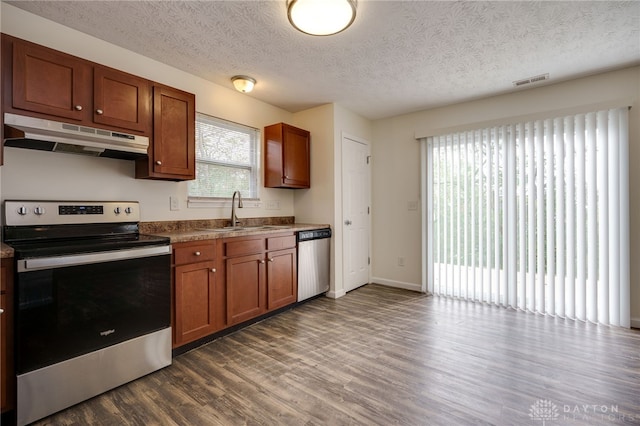 kitchen featuring visible vents, appliances with stainless steel finishes, dark wood-type flooring, under cabinet range hood, and a sink