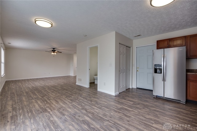 unfurnished living room featuring ceiling fan, a textured ceiling, visible vents, baseboards, and dark wood-style floors