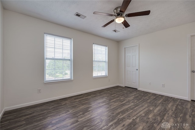 unfurnished room with dark wood-style flooring, visible vents, ceiling fan, a textured ceiling, and baseboards