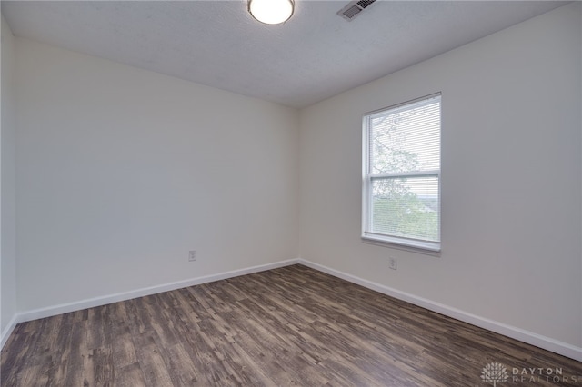 unfurnished room featuring visible vents, dark wood finished floors, and baseboards