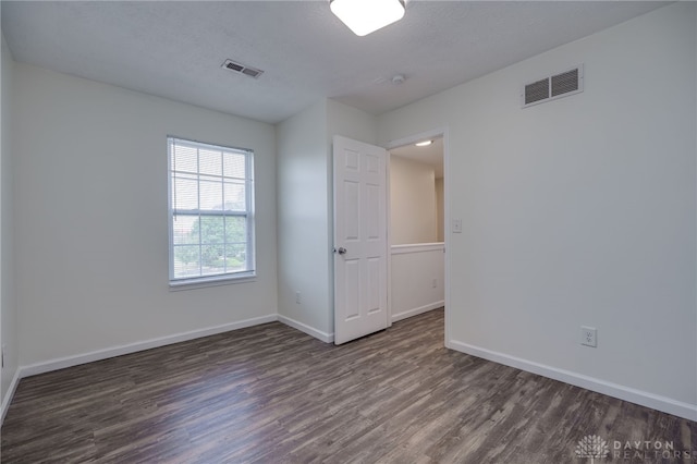 unfurnished room featuring baseboards, a textured ceiling, visible vents, and wood finished floors