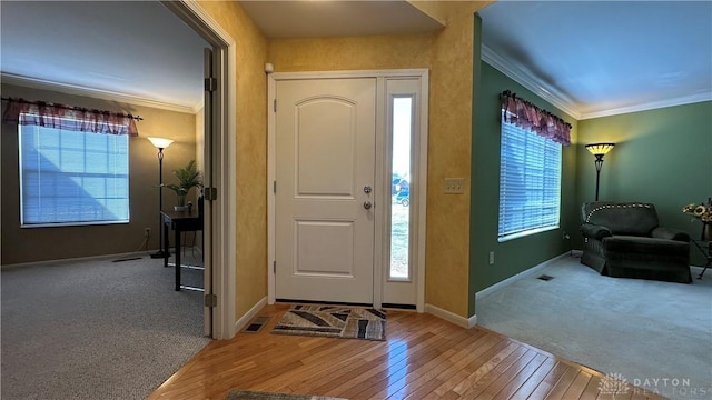 foyer featuring light wood finished floors, ornamental molding, and baseboards