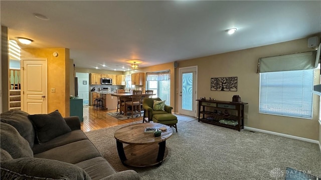 living area featuring light colored carpet and baseboards