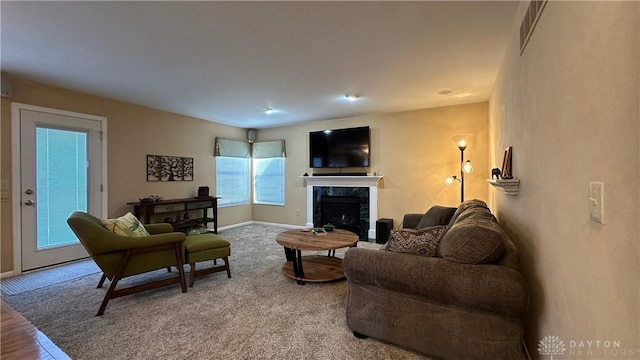 living room with carpet floors, visible vents, a fireplace, and baseboards