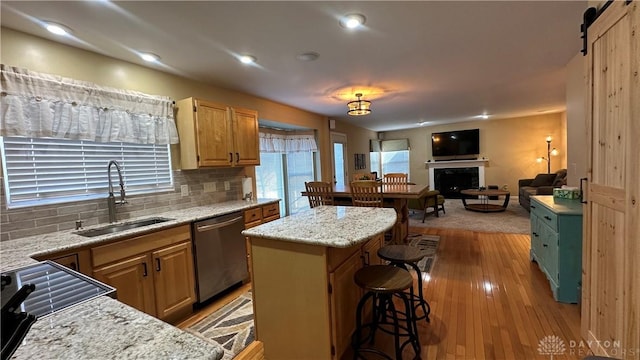 kitchen with decorative backsplash, a center island, stainless steel dishwasher, a sink, and a high end fireplace