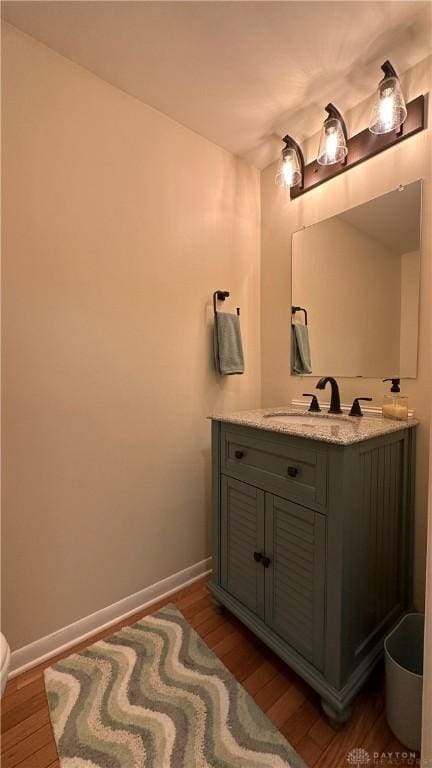 bathroom featuring toilet, wood finished floors, vanity, and baseboards