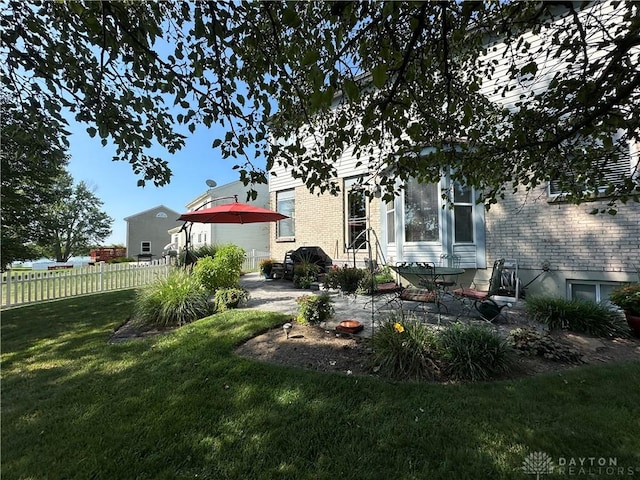 back of property featuring a patio area, fence, a lawn, and brick siding