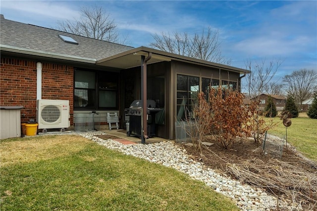 rear view of property featuring brick siding, a sunroom, a yard, roof with shingles, and ac unit