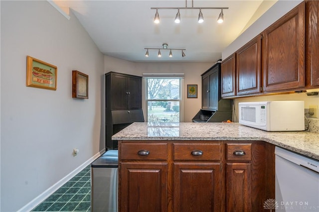 kitchen featuring a peninsula, white appliances, baseboards, and light stone counters