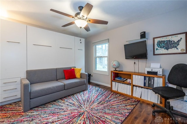 living area with a ceiling fan, baseboards, and wood finished floors