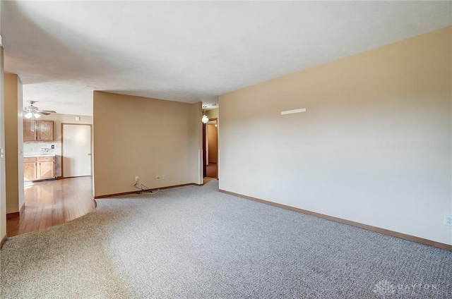 unfurnished living room with ceiling fan, light carpet, and baseboards