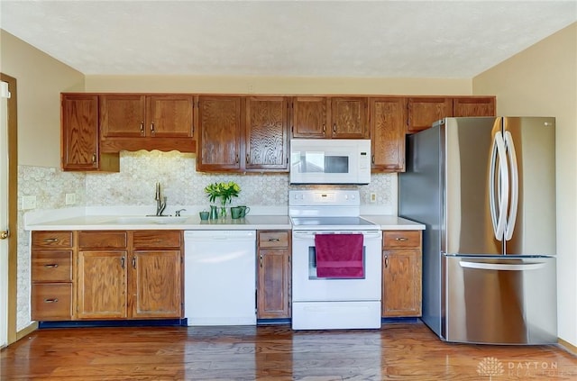 kitchen with light countertops, white appliances, a sink, and brown cabinets