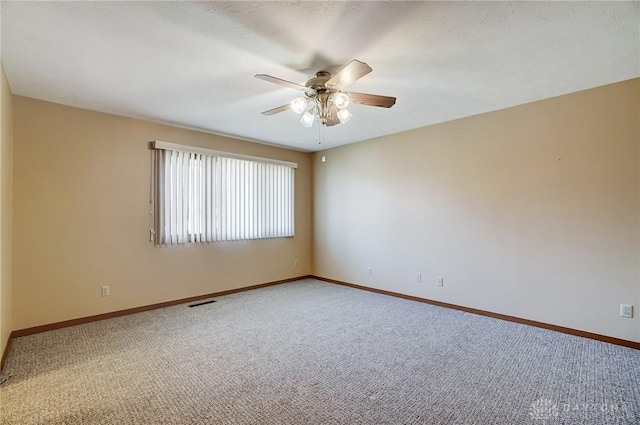 carpeted spare room with ceiling fan and baseboards