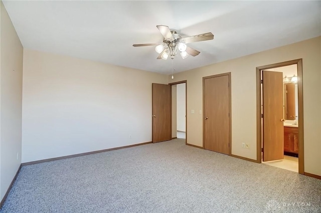 unfurnished bedroom with a ceiling fan, light colored carpet, baseboards, and ensuite bathroom