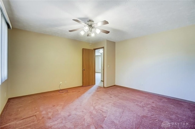 carpeted empty room with ceiling fan and baseboards