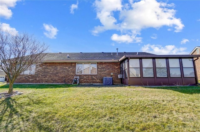 back of property with brick siding, a lawn, and cooling unit