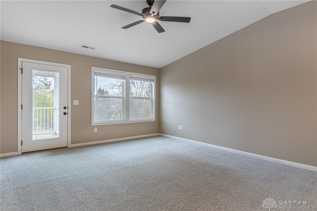 carpeted empty room with plenty of natural light, visible vents, vaulted ceiling, and baseboards