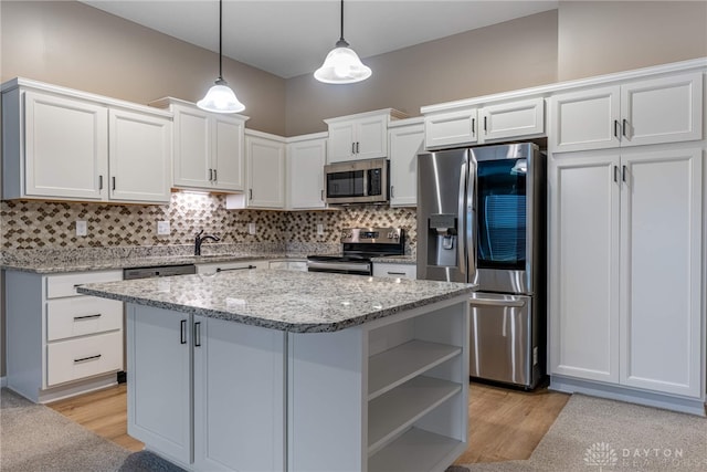 kitchen featuring decorative backsplash, appliances with stainless steel finishes, a center island, decorative light fixtures, and white cabinetry