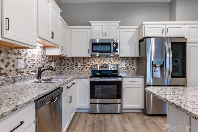 kitchen with light wood-type flooring, appliances with stainless steel finishes, white cabinets, and a sink