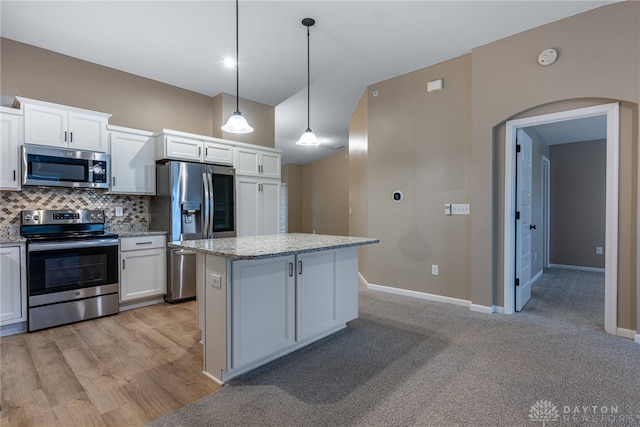 kitchen with tasteful backsplash, arched walkways, a center island, stainless steel appliances, and white cabinetry