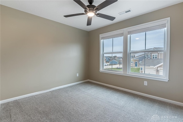 carpeted empty room featuring a ceiling fan, visible vents, and baseboards