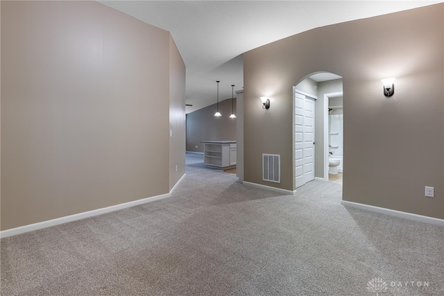 unfurnished room with arched walkways, baseboards, visible vents, and light colored carpet