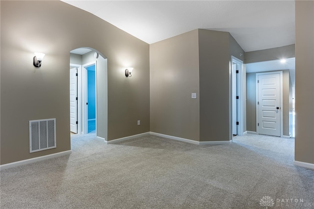 unfurnished room with light carpet, baseboards, visible vents, arched walkways, and lofted ceiling